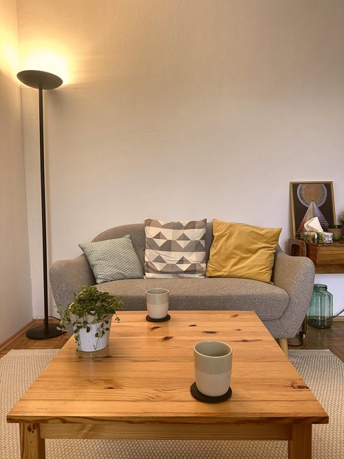 Sofa mit Kissen, Stehlampe und Couchtisch im Praxisraum von Dr. Irina Andreitz in Klagenfurt