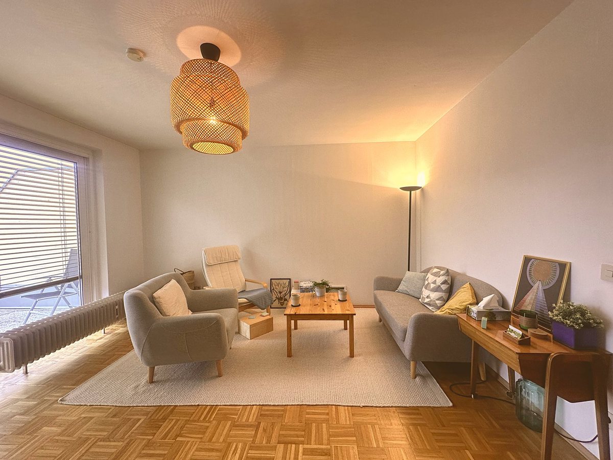 Praxisraum von Dr. Irina Andreitz in Klagenfurt mit Sesseln, Sofa, Couchtisch und großem Fenster